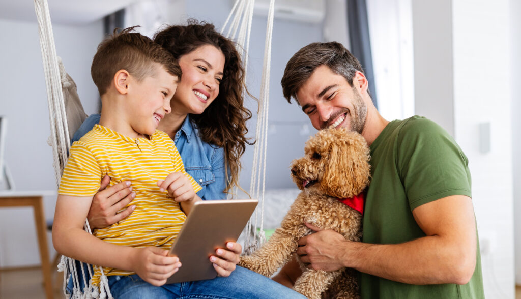 Happy family with modern devices and dog having fun, playing at home